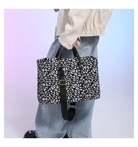 Leopard print tote bag with black wide strap and golden hardware shown on a model