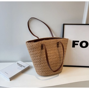 Detailed weave of large capacity straw tote bag with dual brown leather handles