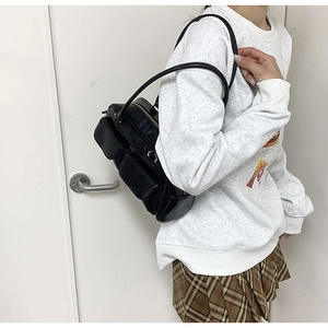 Side view of black PU shoulder bag with multi-pocket design on female model