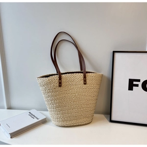Detail showing natural beige raffia weave texture and brown leather handle with metal rivets