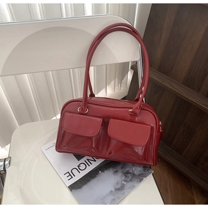 Detailed macro view of the glossy red PU leather texture and front flap pockets on the bag