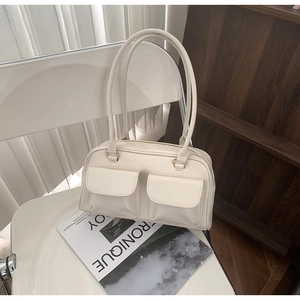 Close-up of cream PU leather shoulder bag with double front flap pockets and slim handles