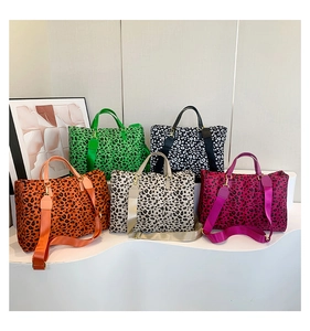 Detailed arrangement of five leopard print tote bags in various vibrant colors on white steps