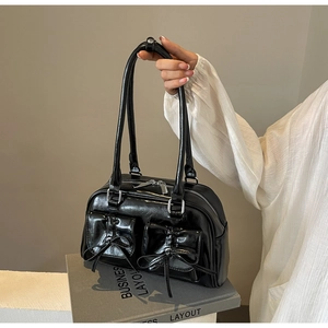 Close-up of black glossy PU leather bowling bag with bow-knot pockets and silver zippers