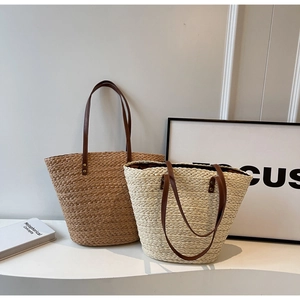 Detail of hand-woven straw tote bags in beige and natural wood tones with leather handles