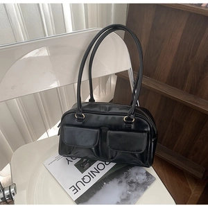 Detail view of retro black PU leather shoulder bag with dual front flap pockets and gold rings