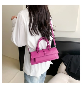 Sac baguette rose vif porté en bandoulière par un mannequin dans un décor épuré