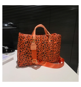 Close-up of leopard print quilted tote bag with orange handle and adjustable strap
