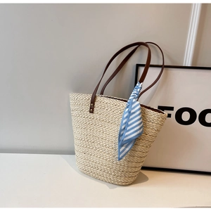 Detailed texture of raffia woven tote with leather strap and blue striped silk scarf