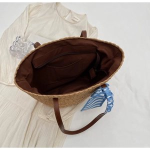 Detail view of woven bucket bag interior with brown lining, pockets and a striped silk scarf