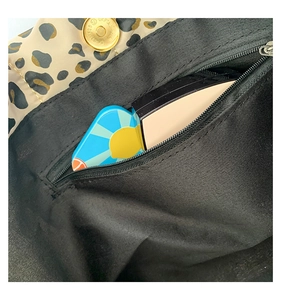 Close-up of leopard tote interior with zipper pocket and golden magnetic snap closure
