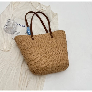 Detail of raffia woven tote with brown leather handles and decorative floral silk scarf