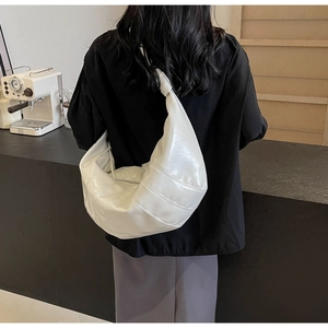 Detailed view of a white glossy crescent hobo bag with knotted strap and vertical stitching