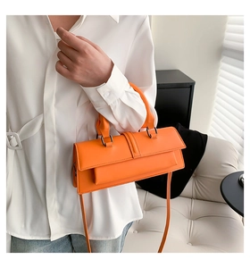 Détail du sac baguette orange vif avec cuir texturé et fine bandoulière réglable