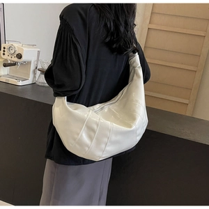 Detailed view of white croissant bag with quilted stitching and wide knotted strap