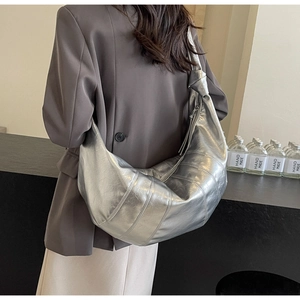 Detailed view of silver crescent tote bag with glossy wrinkled texture on a model