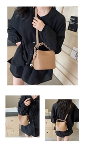 Detail der braunen Bucket Bag aus genarbtem Leder mit Flechtgriff und silbernem Kugelanhänger