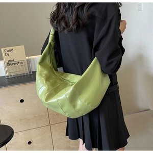 Detail of a bright green large crescent bag with quilted design and wide shoulder strap