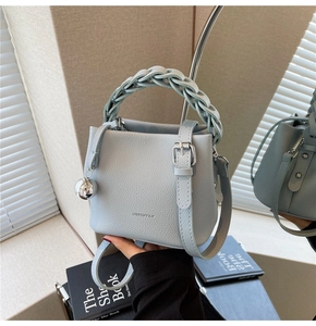 Detailansicht der hellblauen Eimertasche aus Leder mit Flechtgriff und Silberanhänger