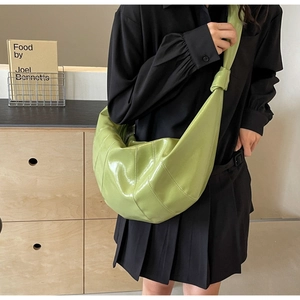 Detail of avocado green half-moon tote bag with vertical stitching and knotted wide strap