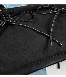 Detail of black tote bag showing durable canvas texture, white stitching, and pleated drawstring