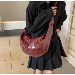 Detailed close-up of a burgundy leather croissant bag with glossy oil-wax finish