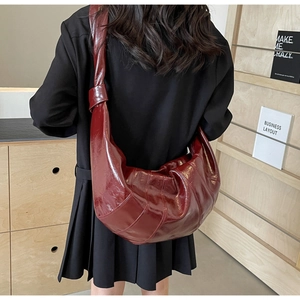 Detailed back view of a burgundy quilted croissant shoulder bag with knot strap detail