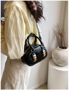 Close-up of black glossy patent leather bowling bag with gold hardware and shoulder strap