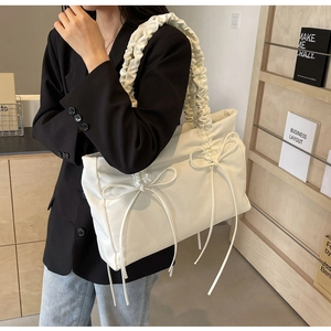 Detail of creamy white tote bag with bow knots and ruffled pleat shoulder straps