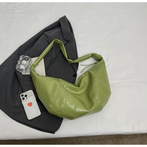 Detailed view of green croissant hobo bag with quilted stitching on a blazer background