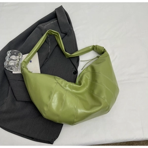 Detail of lime green quilted leather crescent bag on gray blazer background