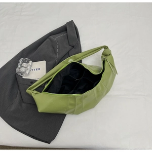 Detail view of grass green faux leather shoulder bag featuring black fabric lining and pockets