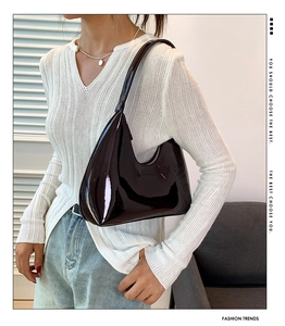 Model wearing a glossy dark hobo bag showing the stylish underarm fit and crescent shape