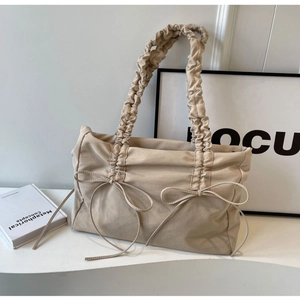 Beige tote bag with pleated straps and bow details for a stylish minimalist look