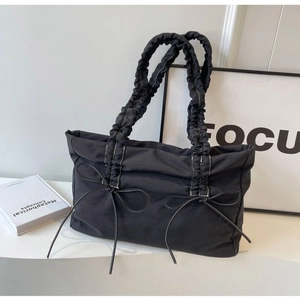 Black tote bag with pleated straps and bow accents featuring white contrast stitching