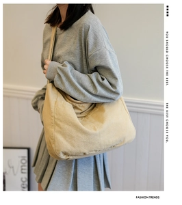 Detailed view of the wide shoulder strap and soft beige canvas texture of the messenger bag
