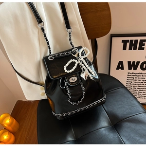 Detail of black leather chain bag with silver twist lock and pearl bow charm accessory