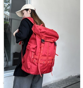 Vista laterale di un grande zaino rosso in nylon impermeabile con coulisse e doppia fibbia