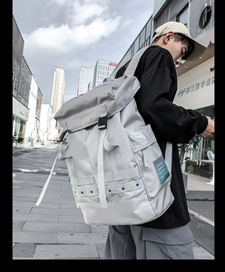 Dettaglio dello zaino tattico grigio con coulisse indossato da un modello in un contesto urbano