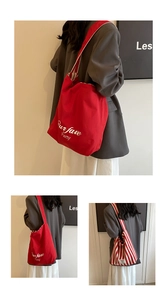 Detail view of large red canvas tote bag with white embroidery and classic vertical stripes