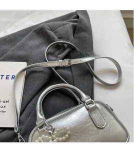 Detail of silver oil wax leather Boston bag with pearl heart charm and strap