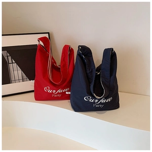 Close-up of red and navy canvas tote bags with white script lettering and minimalist design
