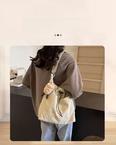 Detail view of cream nylon tote bag with drawstring closure and cute plush bread charm