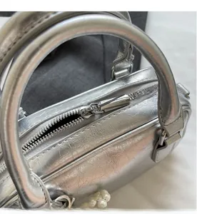 Detail of silver pleated leather mini bag with smooth metal zipper and pearl charm