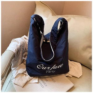 Navy blue quilted tote bag with white text print on a light colored armchair