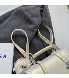 Detail der perlweißen Ledertasche mit silbernen Beschlägen und Plüsch-Augenanhänger