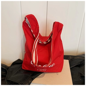 Detail of red canvas tote bag featuring striped woven handles and white party lettering
