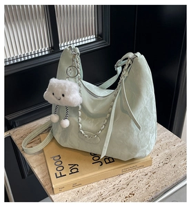 Detail of mint green pleated hobo bag with silver chain and white plush cloud pendant