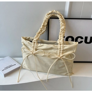 Chic cream white pleated tote bag featuring delicate bow accents and ruffled shoulder strap