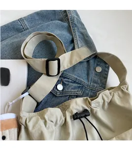 Detail of adjustable wide shoulder strap and black drawstring on beige nylon tote bag